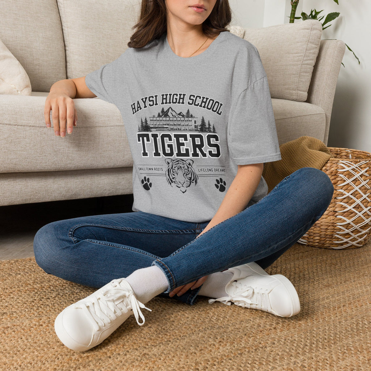 Person wearing a t-shirt with text sitting on the floor in a living room.