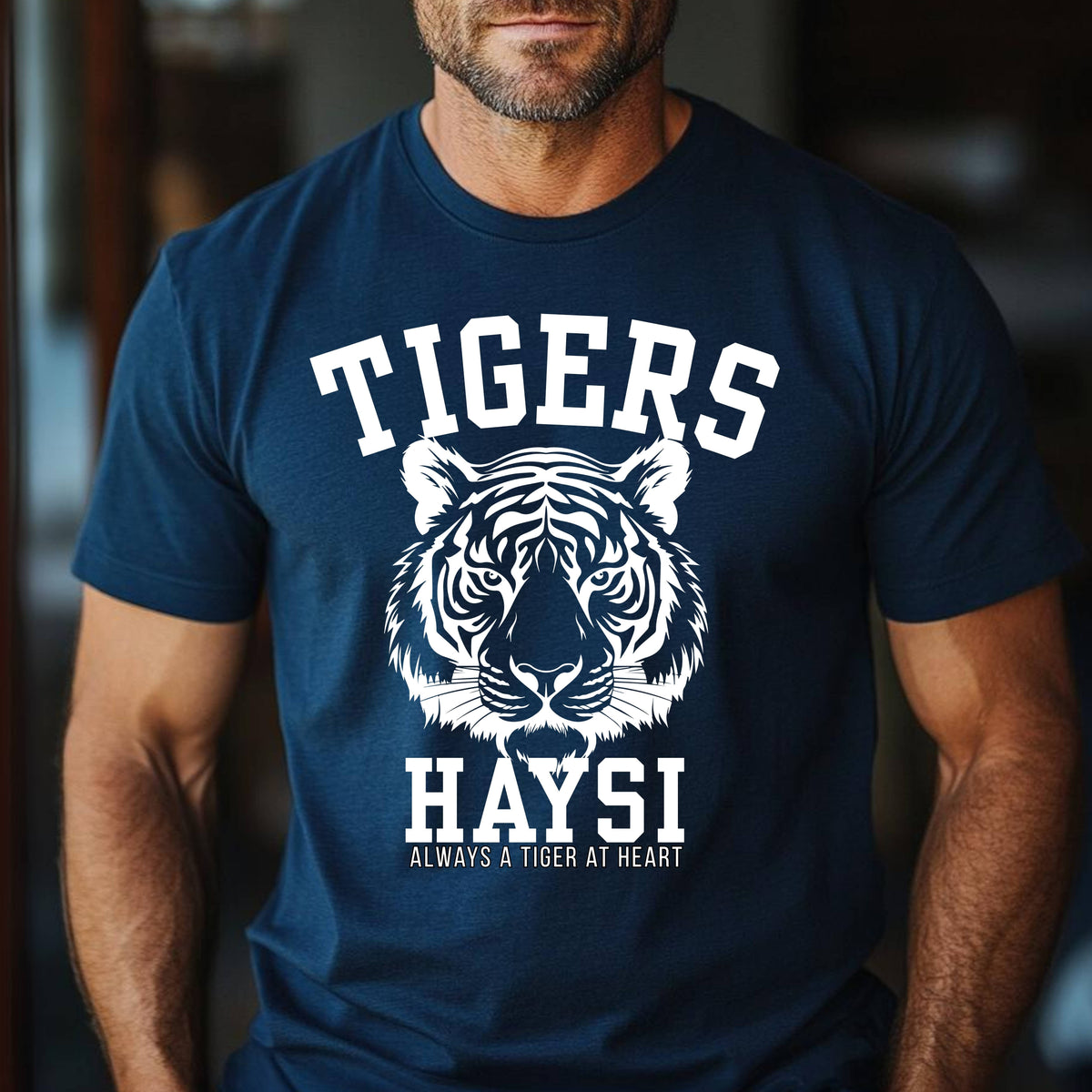 A man wearing a navy blue t-shirt with a white graphic of a tiger's face and the text 'TIGERS HAYSI ALWAYS A TIGER AT HEART'.