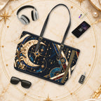 A shoulder bag with a celestial and ornate gold pattern on a dark navy background, styled in a flat-lay arrangement with headphones, sunglasses, a smartphone, and keys on a marble surface.